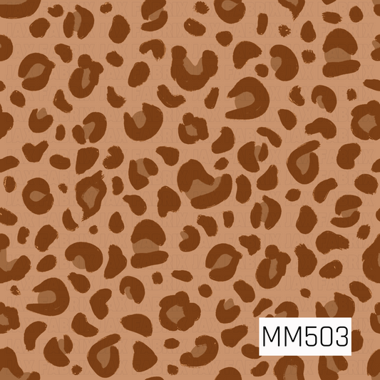 A bold animal print pattern featuring irregular leopard-style spots scattered across a warm caramel tan background. The spots are rendered in a rich chocolate brown with a mix of open rings, curved markings, solid shapes, and smaller scattered flecks. Each marking has slightly rough, hand-painted edges that give the pattern an organic, artistic texture rather than a perfectly polished look. The varied sizes, shapes, and spacing create plenty of movement throughout the design, while the tonal brown palette g
