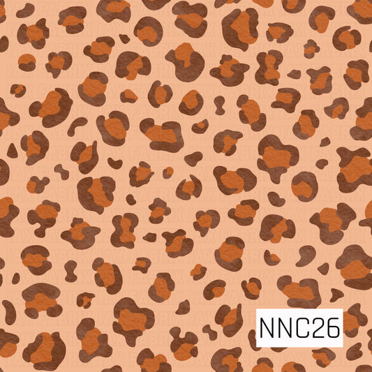 A bold, textured leopard-print pattern featuring irregular chocolate-brown and burnt-orange spots scattered across a warm peach background.
