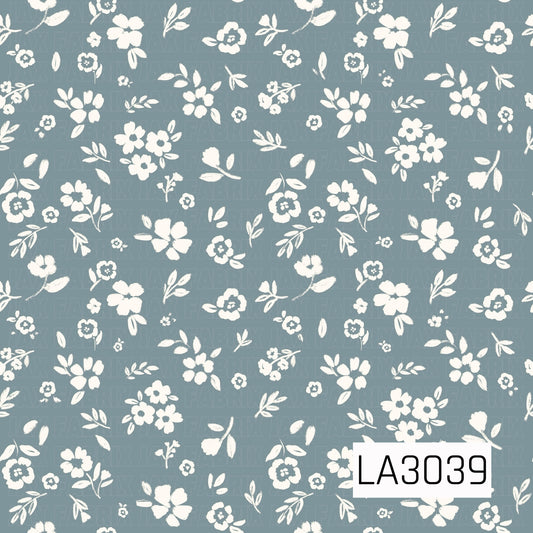 A delicate vintage floral featuring creamy white blossoms, tiny buds, and leafy sprigs scattered across a soft chambray blue background. The hand-painted texture gives it a sweet, timeless cottage feel.
